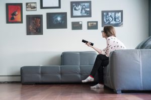 Teenager girl with a TV remote control looking for television program in the living room